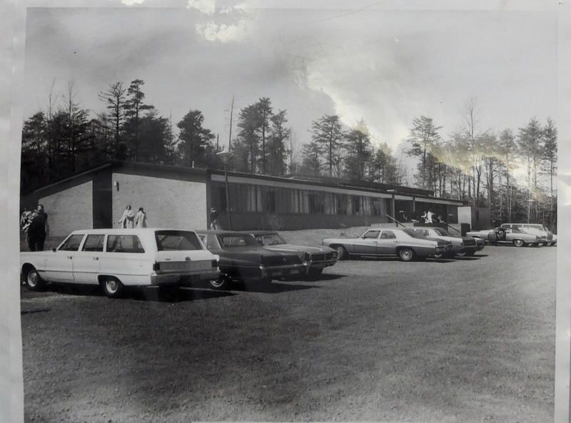 St. George's Methodist Church building with people standing by the entrance and multiple cars parked outside.