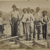 Eight men standing on a railroad under-construction, circa 1862.