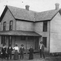 Members of the Tinner family standing outside the exterior of a home in Falls Church Virginia circa 1800.