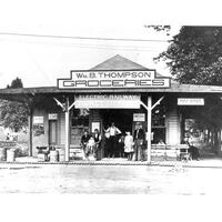 Exterior of the East Falls Church trolley station. Multiple people stand in the doorway looking in the direction of the camera. Circa 1910.